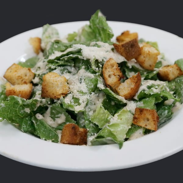A fresh Caesar salad with crisp romaine lettuce, creamy dressing, crunchy croutons, and grated Parmesan cheese.