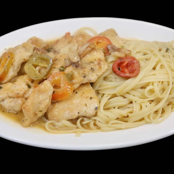 Chicken scaloppine with mushrooms, peppers, and tomatoes, served alongside linguine pasta on a white plate.